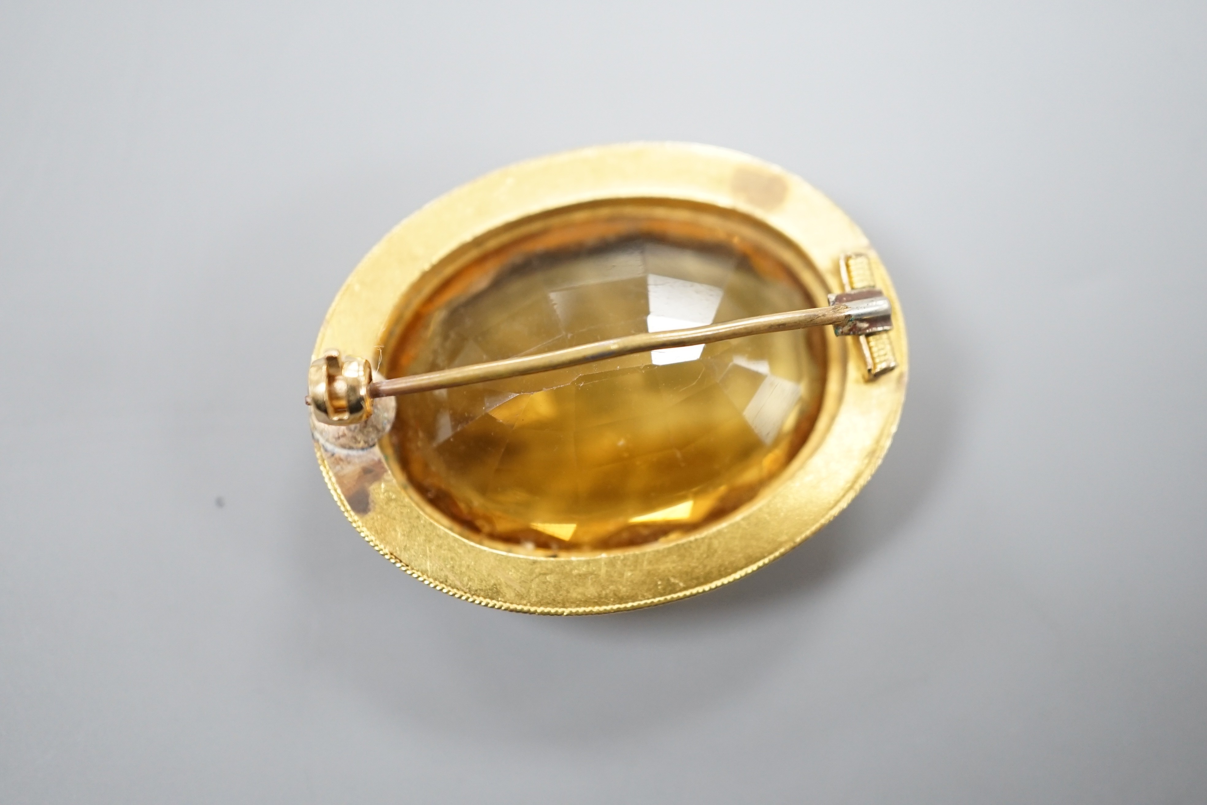 A Victorian yellow metal and citrine set oval brooch, with cannetille work border, 35mm, gross weight 11.3 grams.